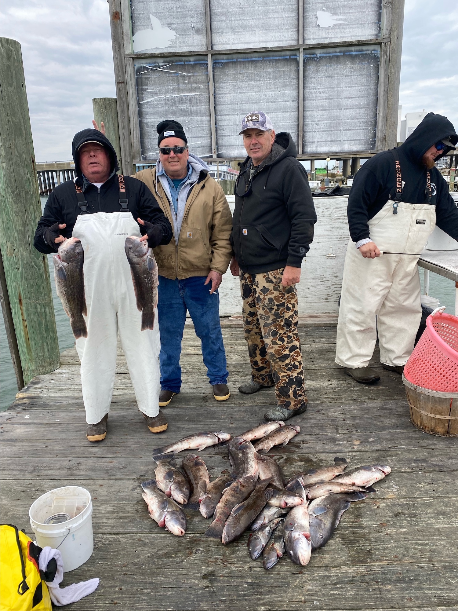 Photo of four men with several types of fish on a dock
