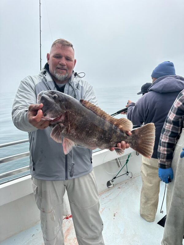 Photo of man on a boat holding a fish
                    